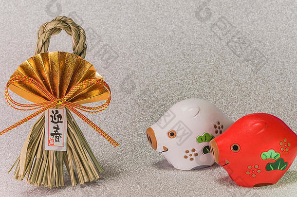 日本新年贺卡上有黑体字“给顺”，意思是用两只野猪的可爱的生肖动物雕像来迎接春天