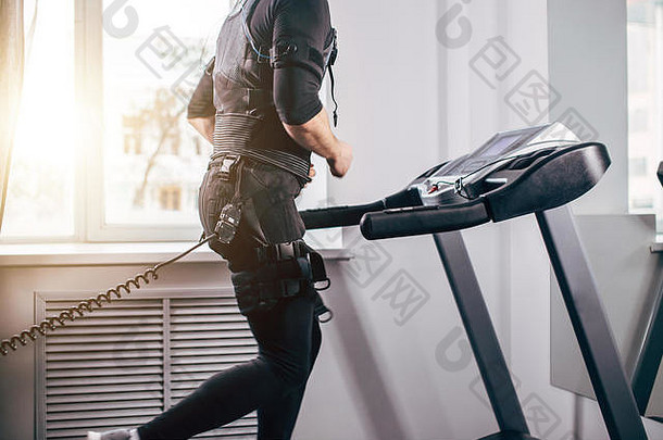身穿黑色套装的男子在健身房跑步机上进行ems训练