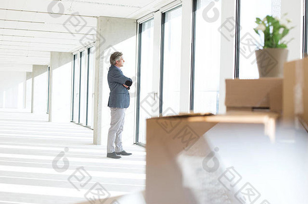 从新办公室窗户向外看的成熟商人侧视图