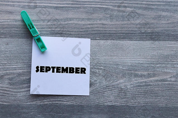 白色便笺纸上的一系列日、月、年（时间概念）文字，由灰色衣夹固定，背景为灰色木板，留有复印空间