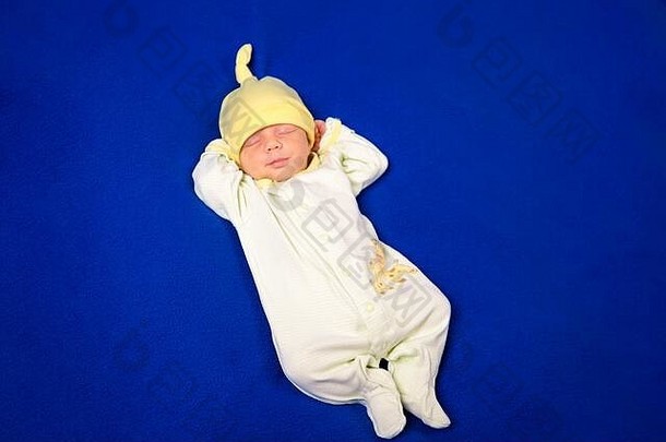 可爱的新生儿睡在蓝色毯子上。穿睡衣小睡的小男孩