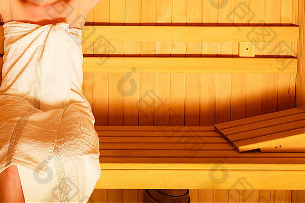 Spa美容养生放松理念。女人身体白毛巾，女孩悠闲地坐在木制桑拿房里