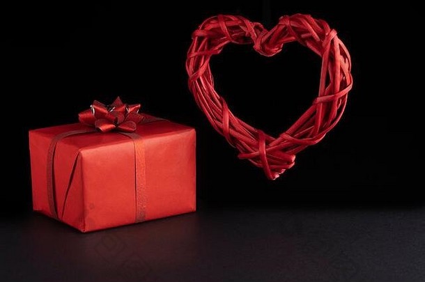 情人节一天概念柳条悬浮红色的心礼物盒子黑色的背景greeeting卡明信片