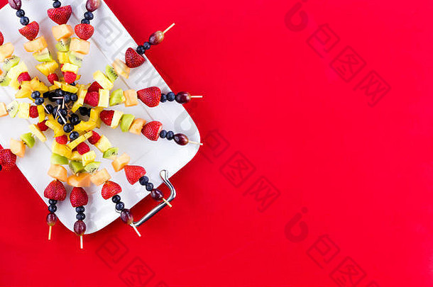 节日安排新鲜的水果烤肉串异国情调的热带夏天水果安排托盘红色的聚会，派对背景
