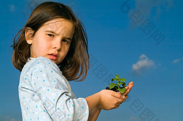 一个女孩拿着植物，用云朵顶着蓝天