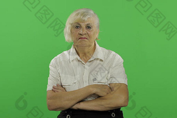 双臂交叉的老妇人。看着摄像机。穿着白衬衫的老奶奶。放置您的徽标或文字。色度键。绿色屏幕背景。情感概念