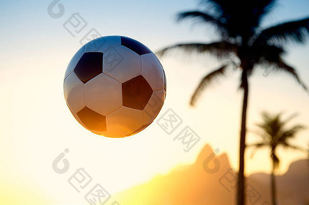 足球足球在巴西里约热内卢上空金色夕阳的天空中飞行，两兄弟在巴西的伊尔茅斯山上