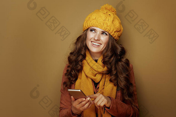 沉思的优雅的女人黄色的贝雷帽围巾智能手机挂社会媒体米色背景