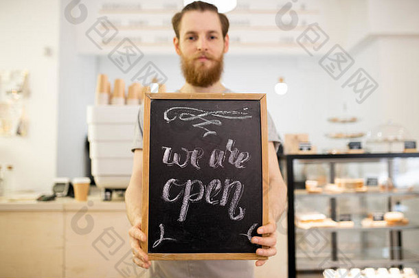 咖啡师手持碑文“我们是开放的”
