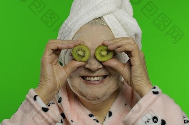 成人高级高加索人女人祖母浴袍泡沫脸面具半猕猴桃应用眼睛孤立的浓度关键背景美程序成熟的爷爷奶奶人