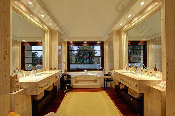 灯光两侧的大镜子和脸盆上方的照明，以及瓷砖地板上奶油羊毛地毯的现代浴室