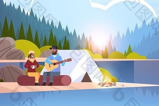 夫妇游客徒步旅行者放松营非洲美国男人。玩吉他女朋友坐着日志徒步旅行概念日出景观自然