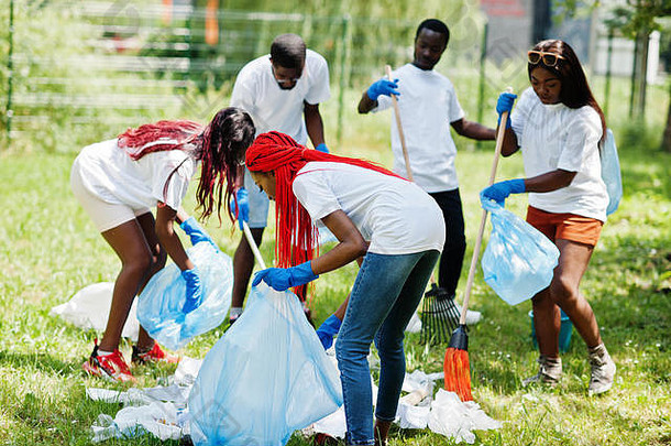 一群快乐的非洲志愿者带着垃圾袋在公园里垃圾。非洲志愿者、慈善、人与生态理念。