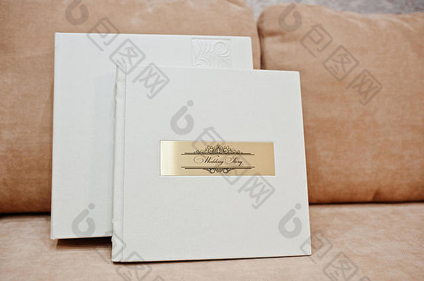 沙发上放着印有金色铭文的白色皮革婚礼相册或相册。