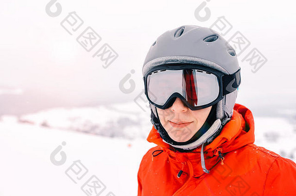 一位滑<strong>雪</strong>妇女的肖像，戴着头盔和滑<strong>雪镜</strong>，背景是雾蒙蒙的山脉