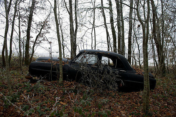 一边视图废弃的黑色的古董车说谎被遗忘的寒冷的森林