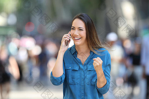 兴奋的女人在街上通过电话收到好消息