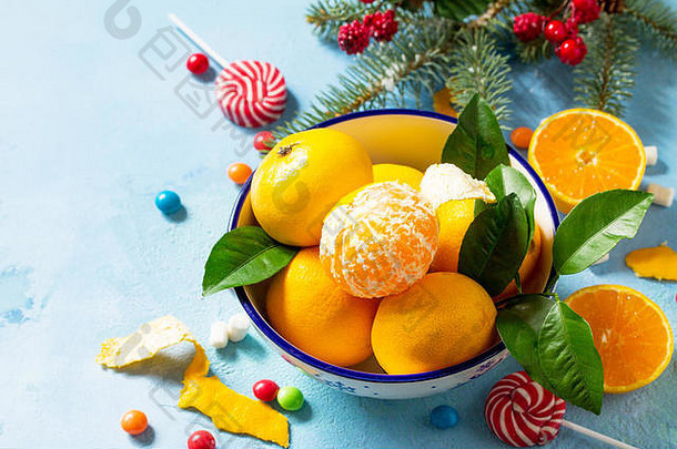 新鲜的多汁的橘子碗各种圣诞节糖果圣诞节分支机构云杉蓝色的混凝土背景复制空间