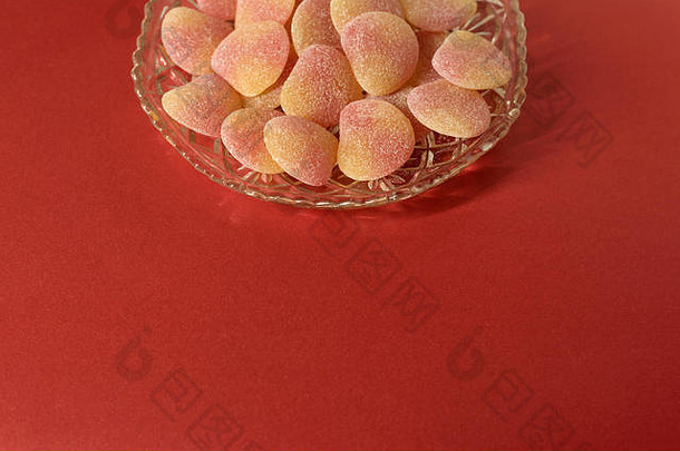 糖化果冻糖果装在水晶切割玻璃盘中-最小的红色背景-以设计元素为中心，空间