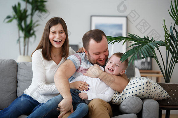 快乐的父母和儿子坐在灰色沙发上的全家福