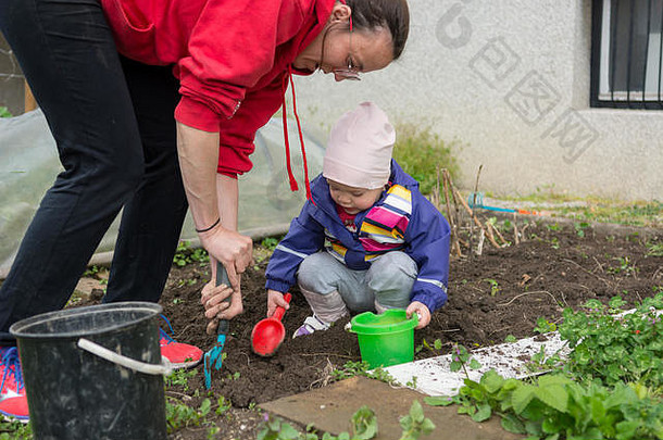 小女孩探索花园，帮助进行春季大扫除。