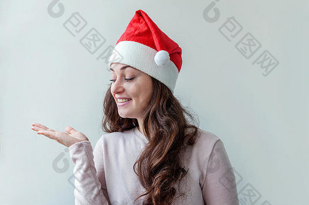 美丽的女孩长头发红色的圣诞老人老人他显示开放棕榈手孤立的白色背景年轻的女人肖像真正的情绪快乐圣诞节一年假期