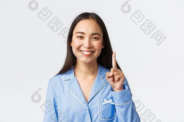 穿着蓝色睡衣的快乐迷人的亚洲女人的特写镜头，展示了一号人物、一个手指和微笑的白色牙齿，解释了主要规则或概念