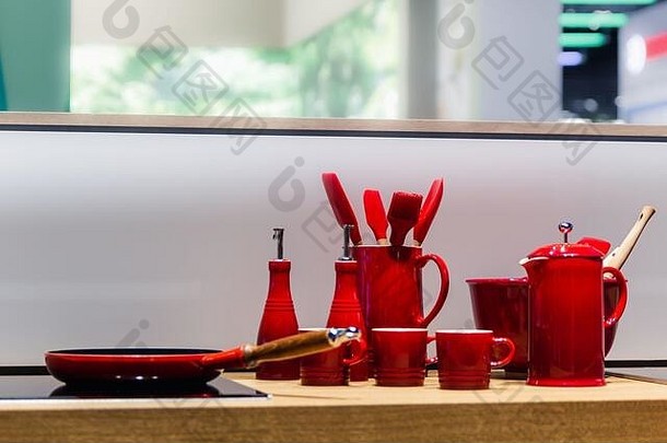 白色背景木质桌子上的闪亮新红色厨房用具