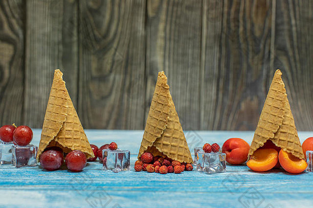 浆果和水果冰淇淋。木质背景上的华夫格蛋卷中平铺着各种新鲜水果、杏子、草莓、葡萄。夏季甜<strong>点菜单</strong>概念。冰淇淋制作