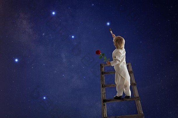 美丽的蹒跚学步的男孩toxedo穿着王子故事持有红色的玫瑰绘画星星天空
