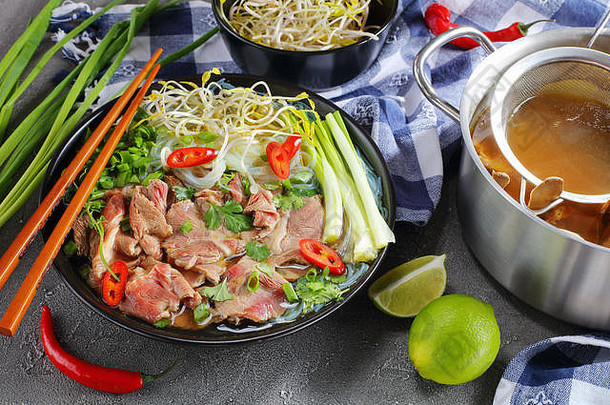 越南汤巨像大米面条生牛里脊肉牛肉片豆豆芽黑色的碗筷子热牛肉骨头肉汤不锈钢锅