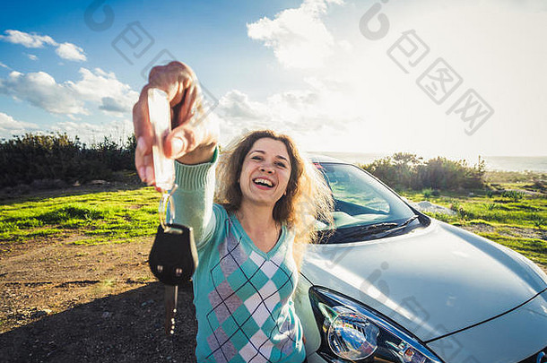 年轻快乐微笑的女人展示新车钥匙