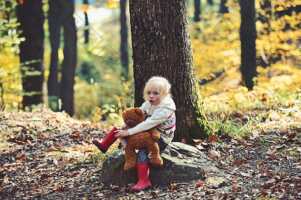 活跃的小女孩和泰迪熊在秋天的森林里。在树林中积极休息和活动，呼吸新鲜空气。