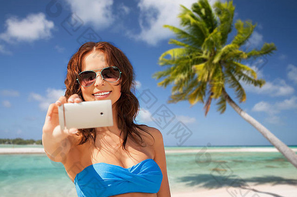 女人采取自拍智能手机海滩
