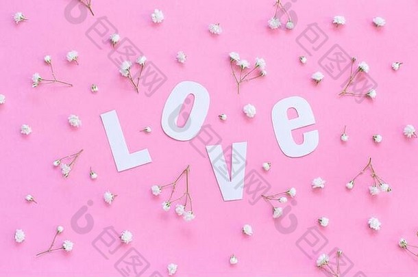 浅粉色背景顶视图上的白色小花和爱情文字