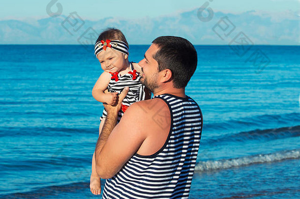 快乐的父亲和可爱的小女儿在海滩上玩耍。