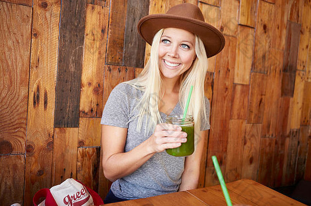快乐健康的年轻女子在咖啡馆里喝着新鲜榨好的果汁