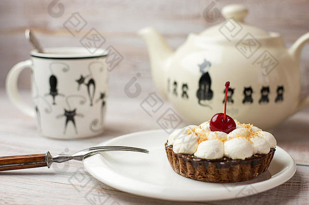 茶杯、茶和蛋糕，桌上放一颗樱桃