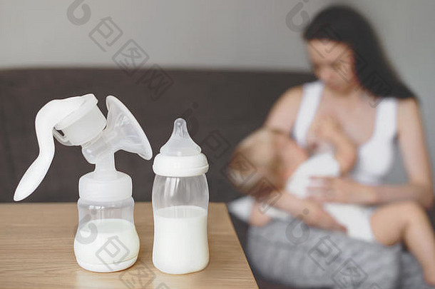 奶瓶和吸奶器以母乳为背景，母亲用手抱着并哺乳婴儿。<strong>妇幼保健</strong>。