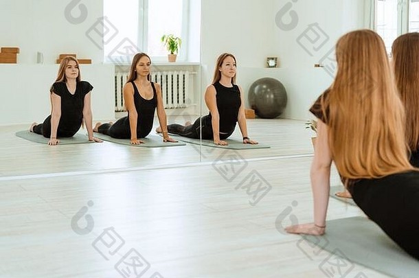 伸展运动。一群穿着黑色制服的年轻女孩正在体育<strong>馆</strong>里做伸展训练。<strong>瑜伽</strong>，<strong>瑜伽</strong>，健身，锻炼。