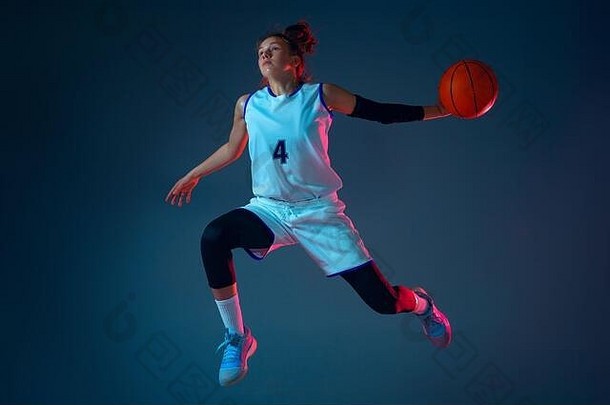 目标年轻的高加索人女篮球球员蓝色的工作室背景霓虹灯光运动行动概念体育运动运动能源动态健康的生活方式培训练习