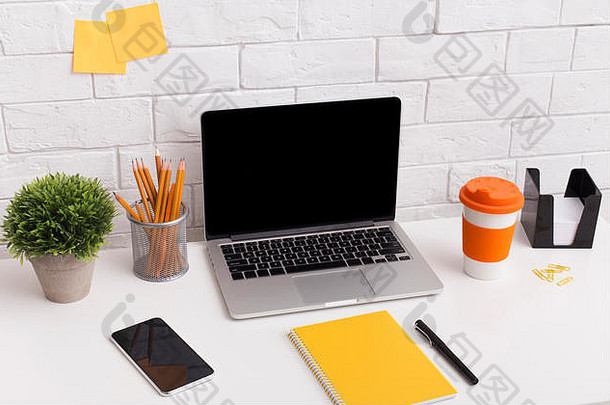 橙色风格的工作场所，白色办公桌上有笔记本电脑