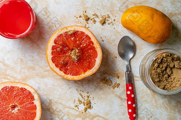 新鲜葡萄柚和鲜榨柑橘果汁，红糖，健康早餐，放在浅色大理石桌面上