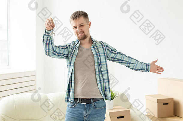 年轻英俊的小伙子站在起居室里，拿出新公寓的钥匙。年轻家庭的抵押贷款和住<strong>房贷</strong>款概念。