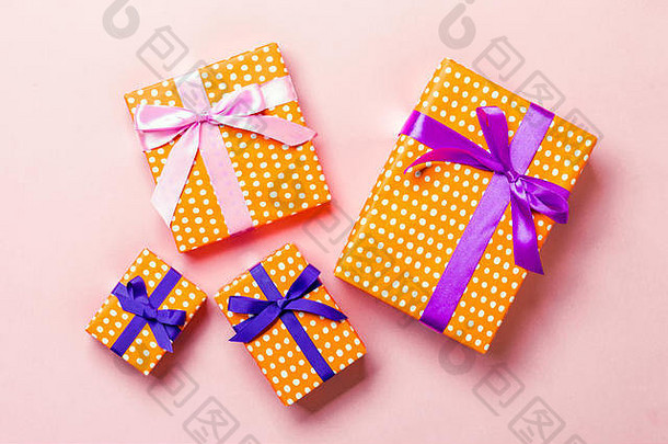 顶视圣诞礼品盒，粉红色背景上有紫色和粉红结。