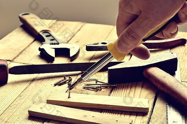 手持工具。锤子、平锉刀、钳子、螺丝刀、活动扳手、螺钉、木板和刀片，背景为天然木质。