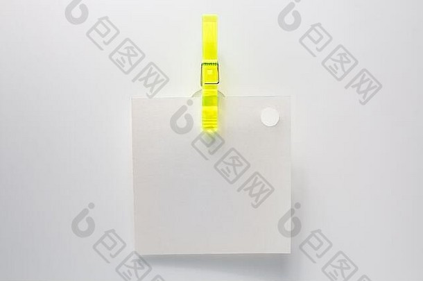 一张空白的便条，用黄色的夹子挂在白色的墙上。办公室