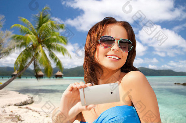 女人采取自拍智能手机海滩