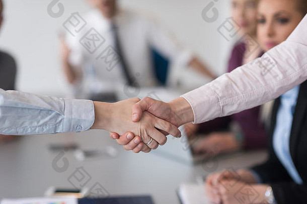在现代创业公司<strong>商务办公</strong>室内部，女企业家在团队会议上与一群人握手的<strong>场景</strong>模糊不清