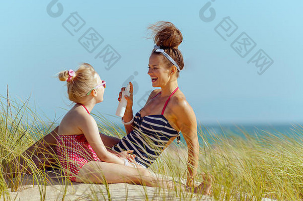 微笑的现代母亲和孩子穿着泳衣在海边晒太阳。防晒霜SPF或<strong>驱</strong>虫剂或<strong>蚊</strong>虫叮咬药物或护发素